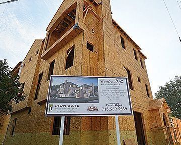 Construction site of a multi-story wood-framed building. Sign advertising 