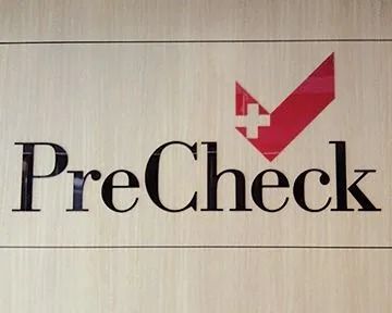 PreCheck logo: black text on wood; red checkmark with white cross.