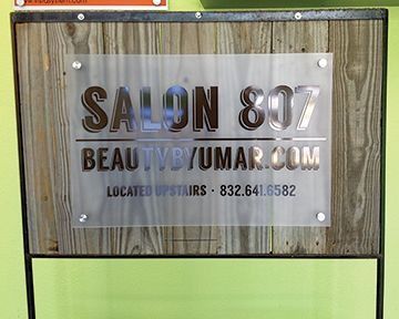 Sign for Salon 807, with website and phone number, attached to wood.