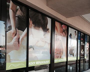 Windows of a business showing foot reflexology and acupressure. Images of massage with text.