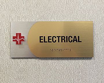 Electrical room sign with red cross and pulse symbol.