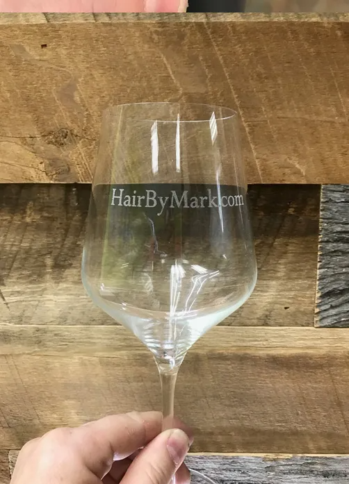 Person holding a clear wine glass engraved with 