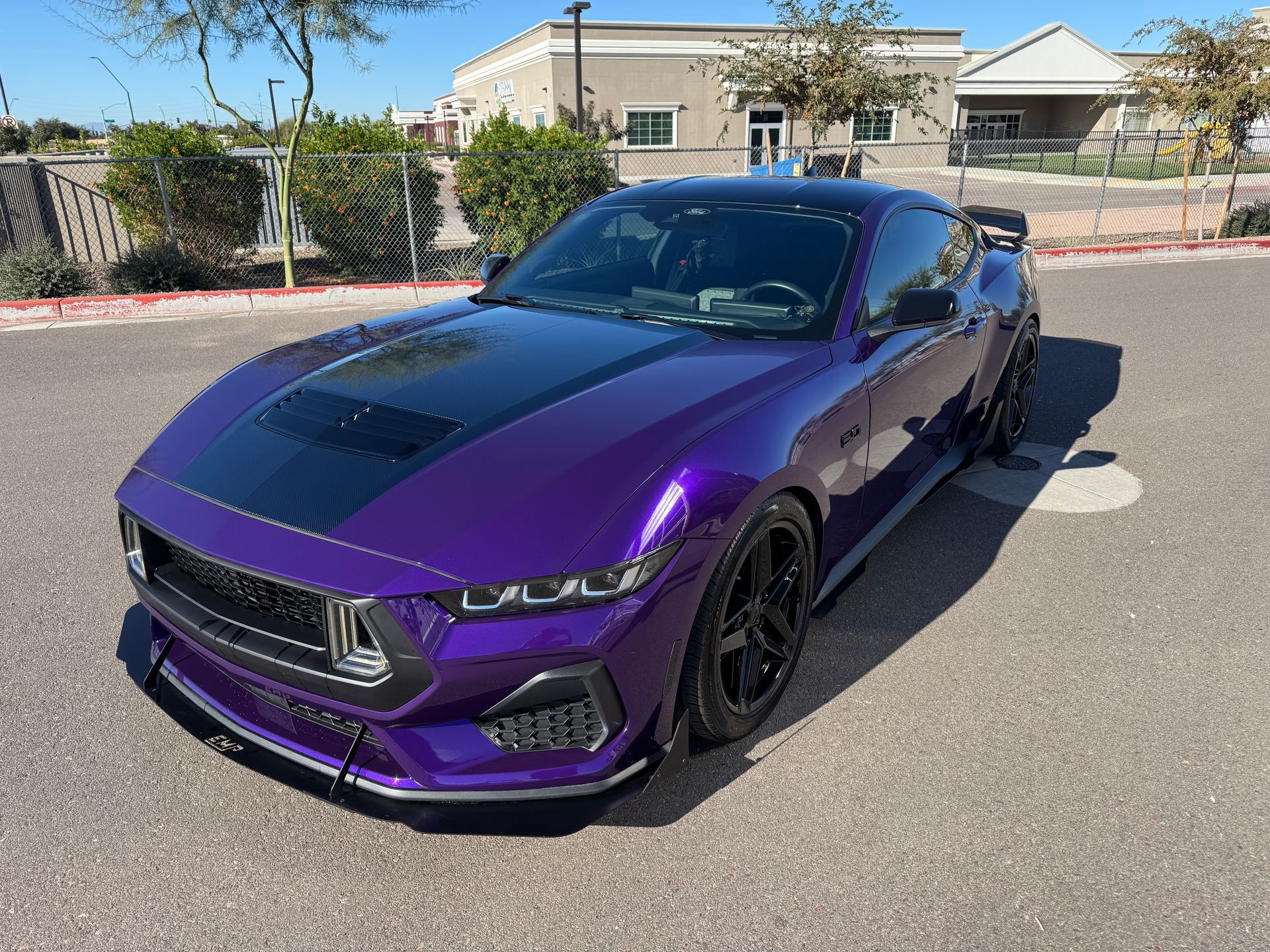 A purple sports car is parked on a street in front of houses