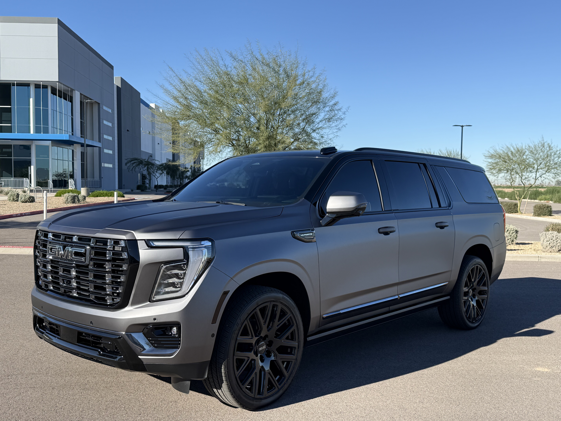 Gray GMC SUV parked outside a modern building on a sunny day