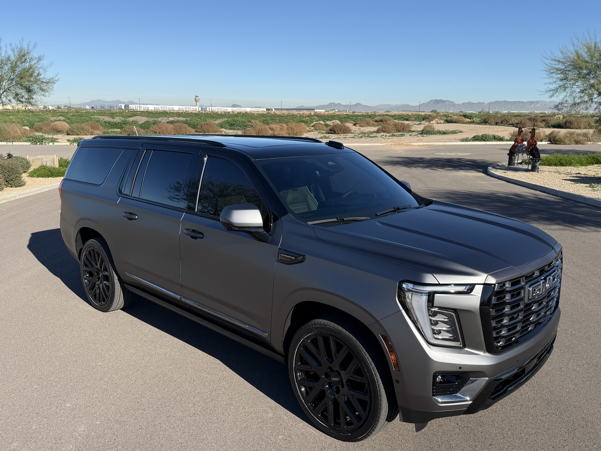 Gray SUV parked on a road beside a desert landscape under a clear sky