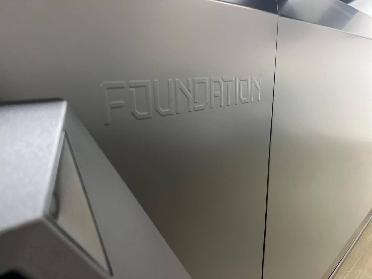 Embossed “FOUNDATION” text on a metallic gray surface with a sharp angular corner.