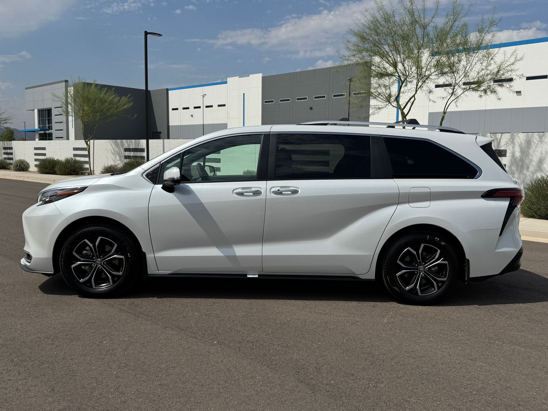 White minivan parked on a street in front of modern buildings on a sunny day