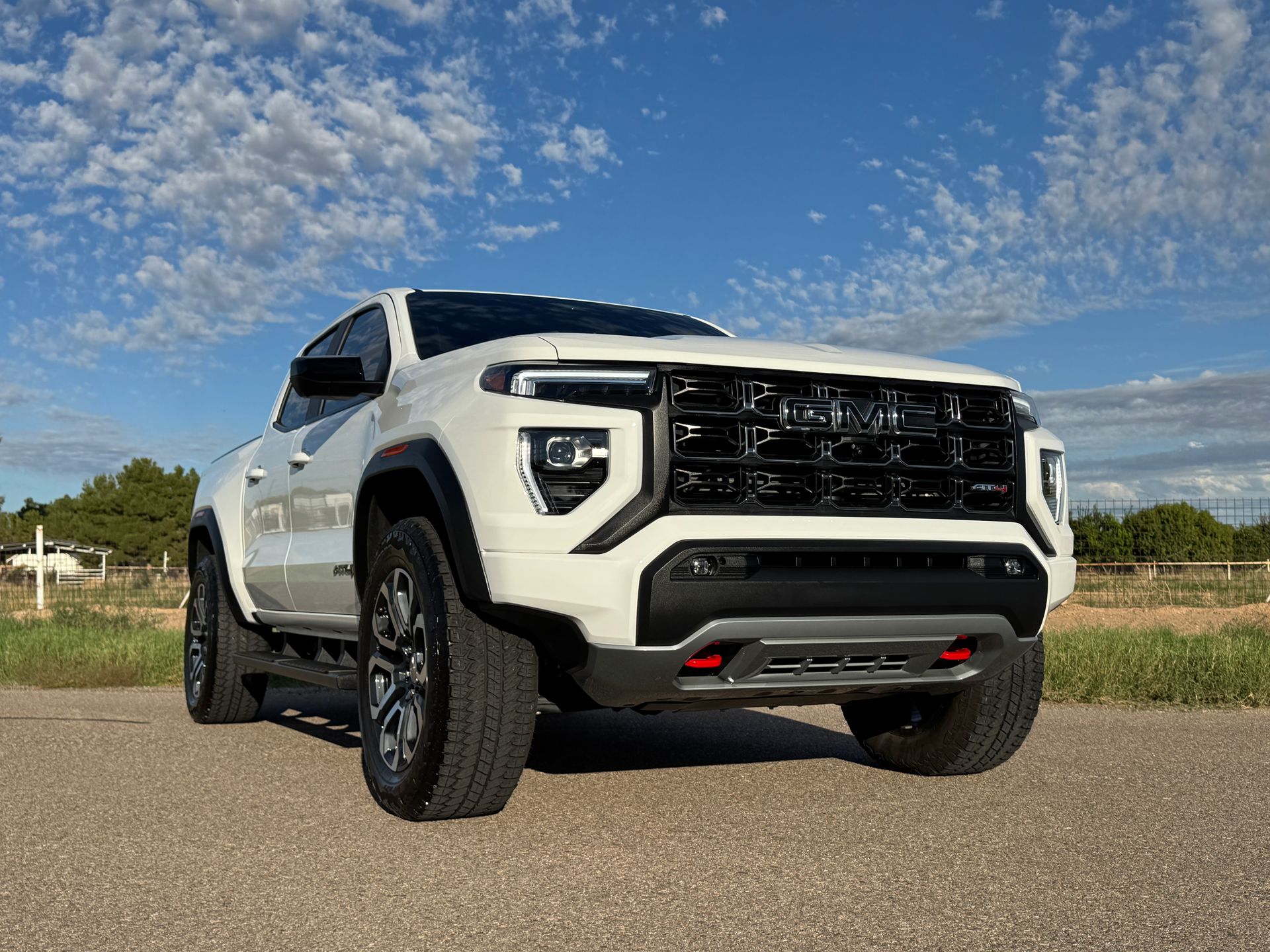 White off-road pickup truck on a dirt road under a blue sky, front three-quarter view