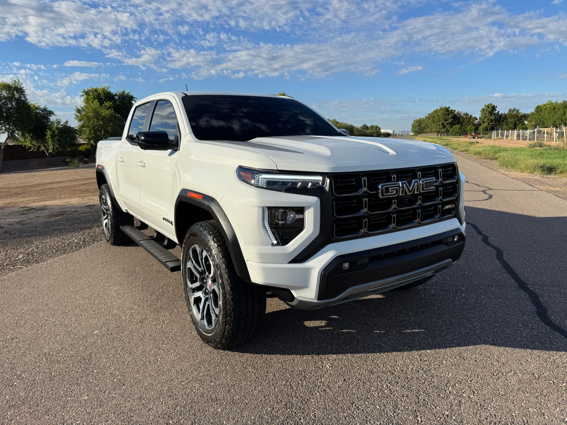 White pickup truck parked on a road under a blue sky, front three-quarter view