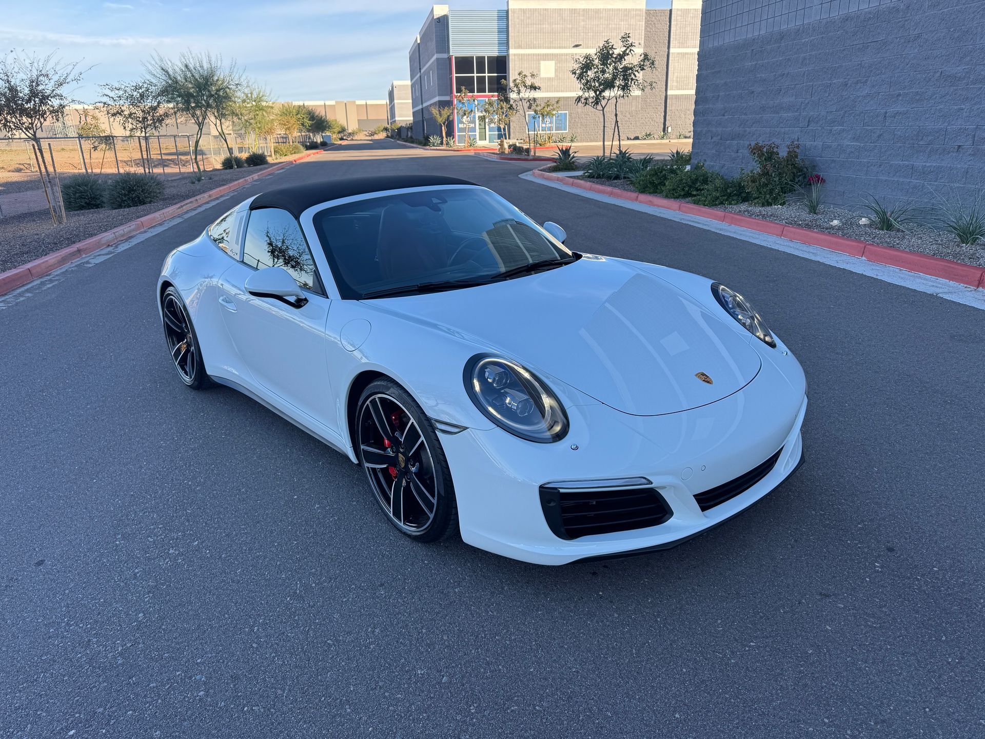 White Porsche sports car parked on a road outside a modern building at dusk