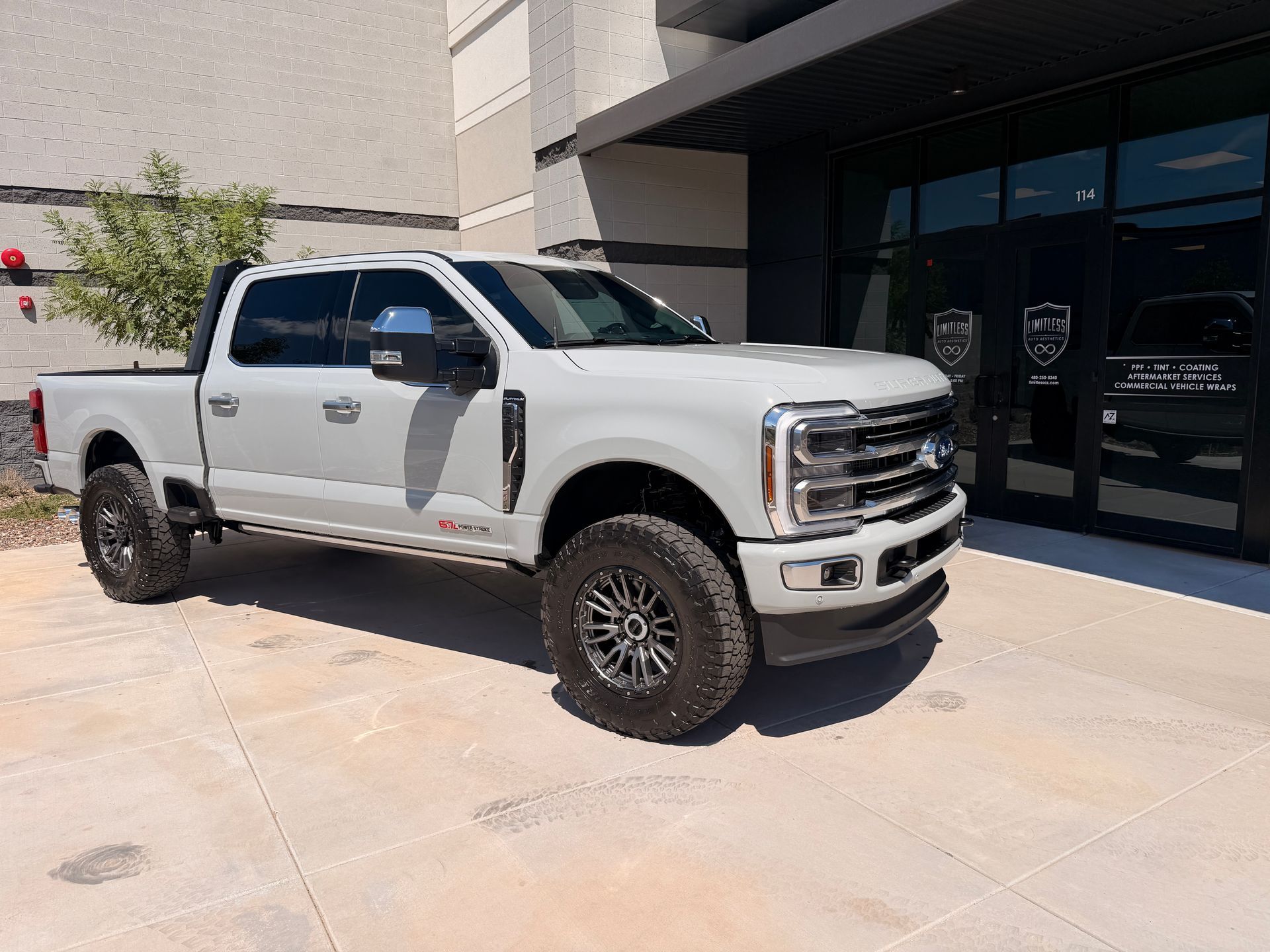 A white pickup truck parked outside a building with glass doors.