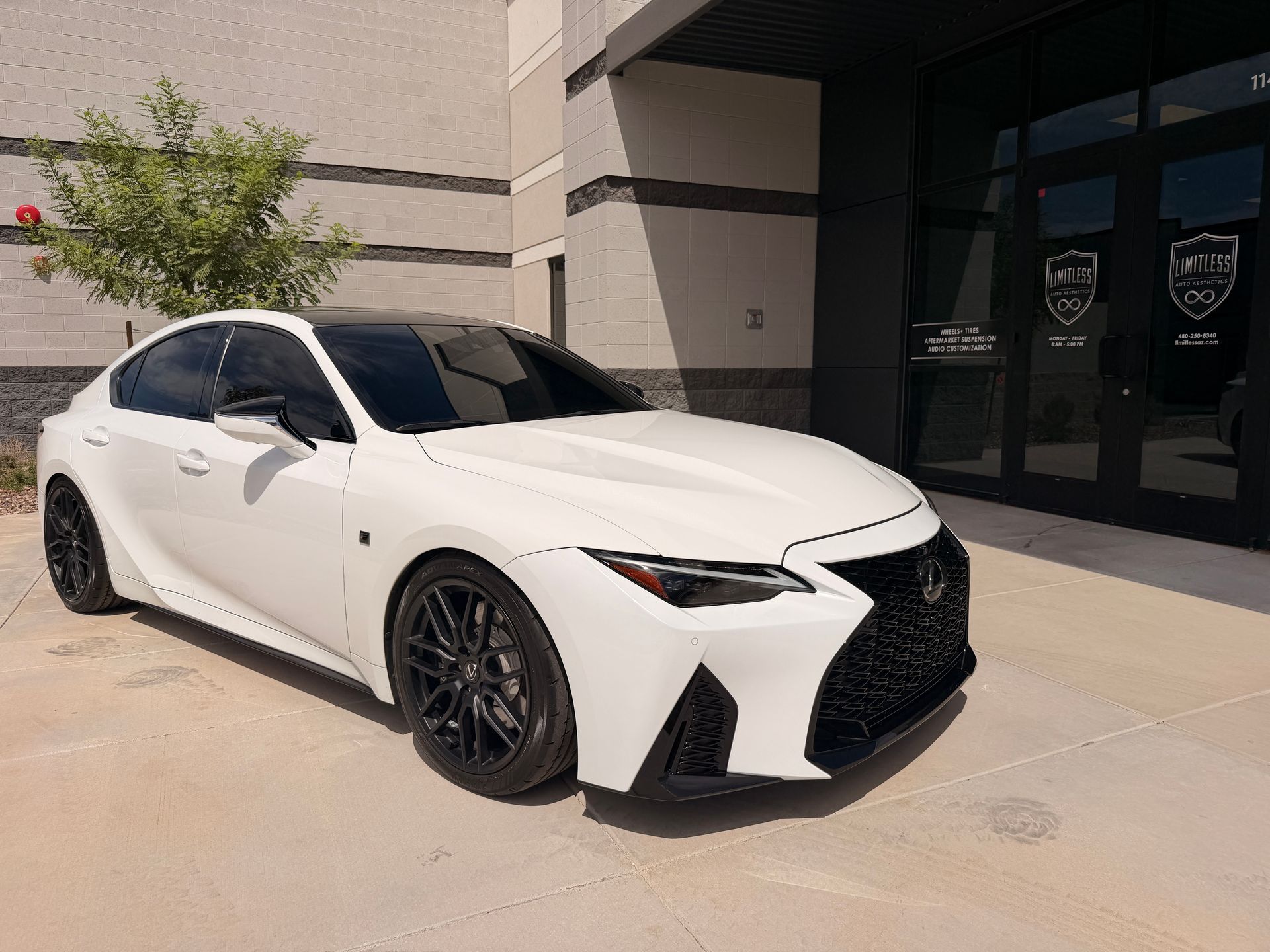 White sports sedan parked outside a modern building in daylight