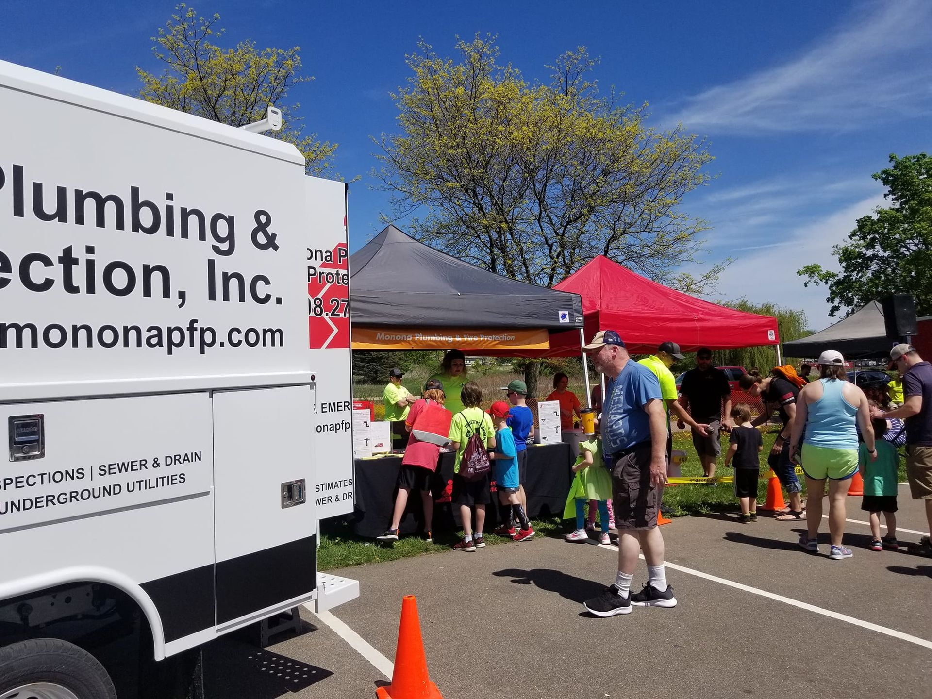 A group of people are standing in front of a plumbing truck