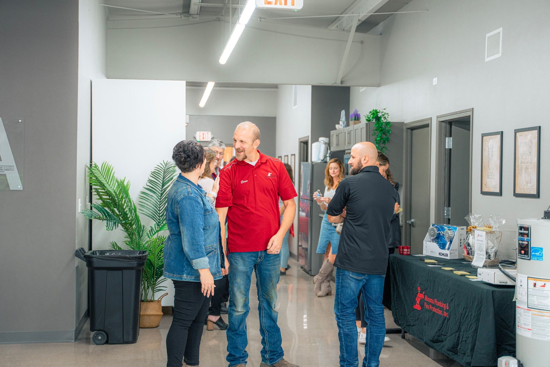A group of people are standing in a hallway talking to each other.