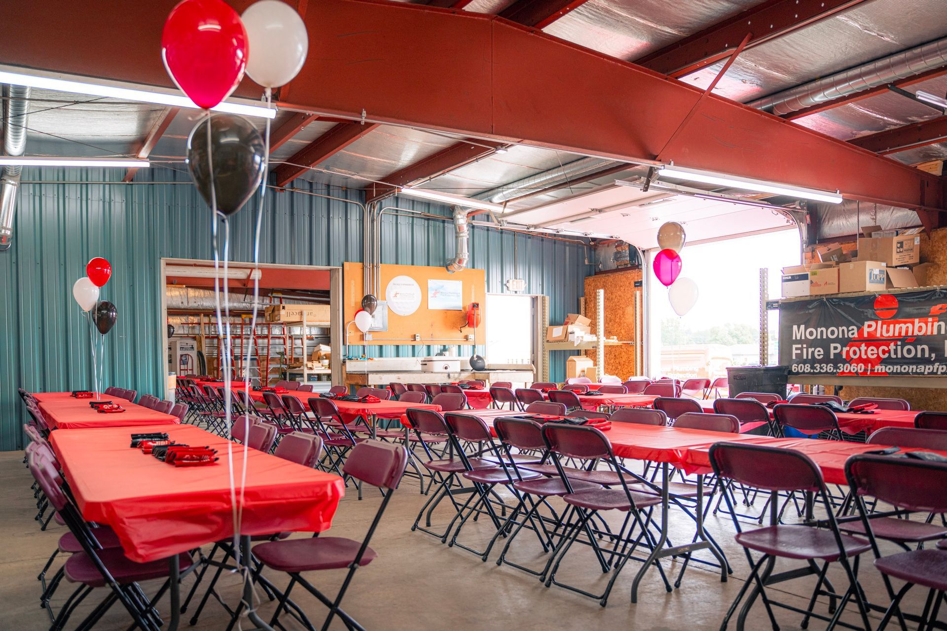 A large room with tables and chairs and balloons hanging from the ceiling.
