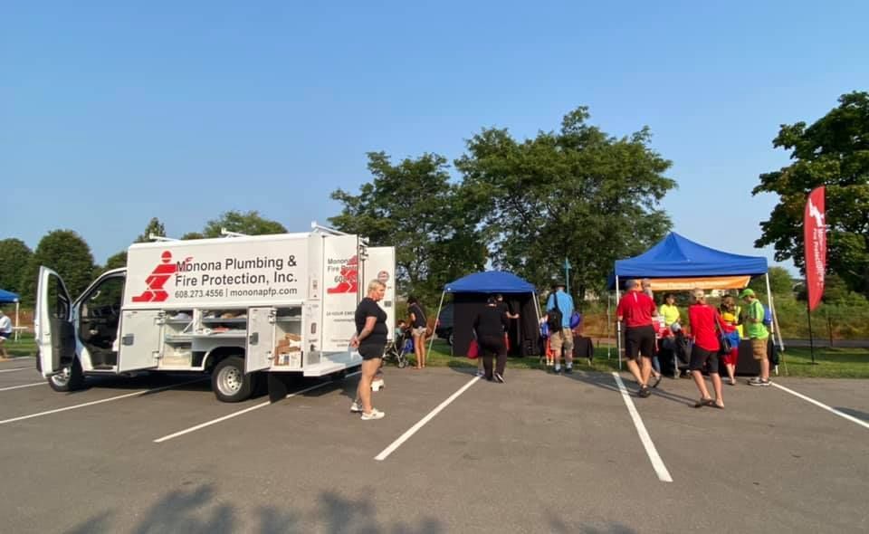 A white van is parked in a parking lot next to a group of people.
