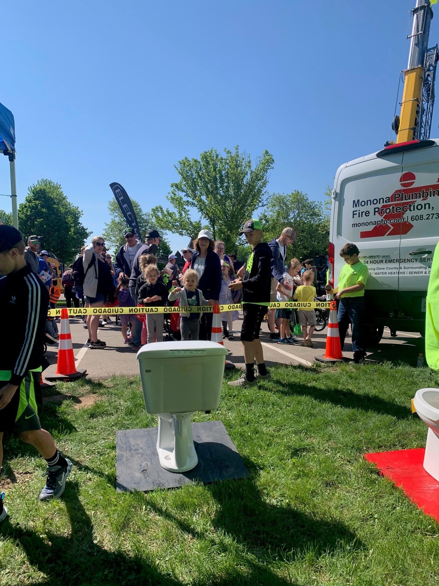 A group of people are standing around a toilet in a field.