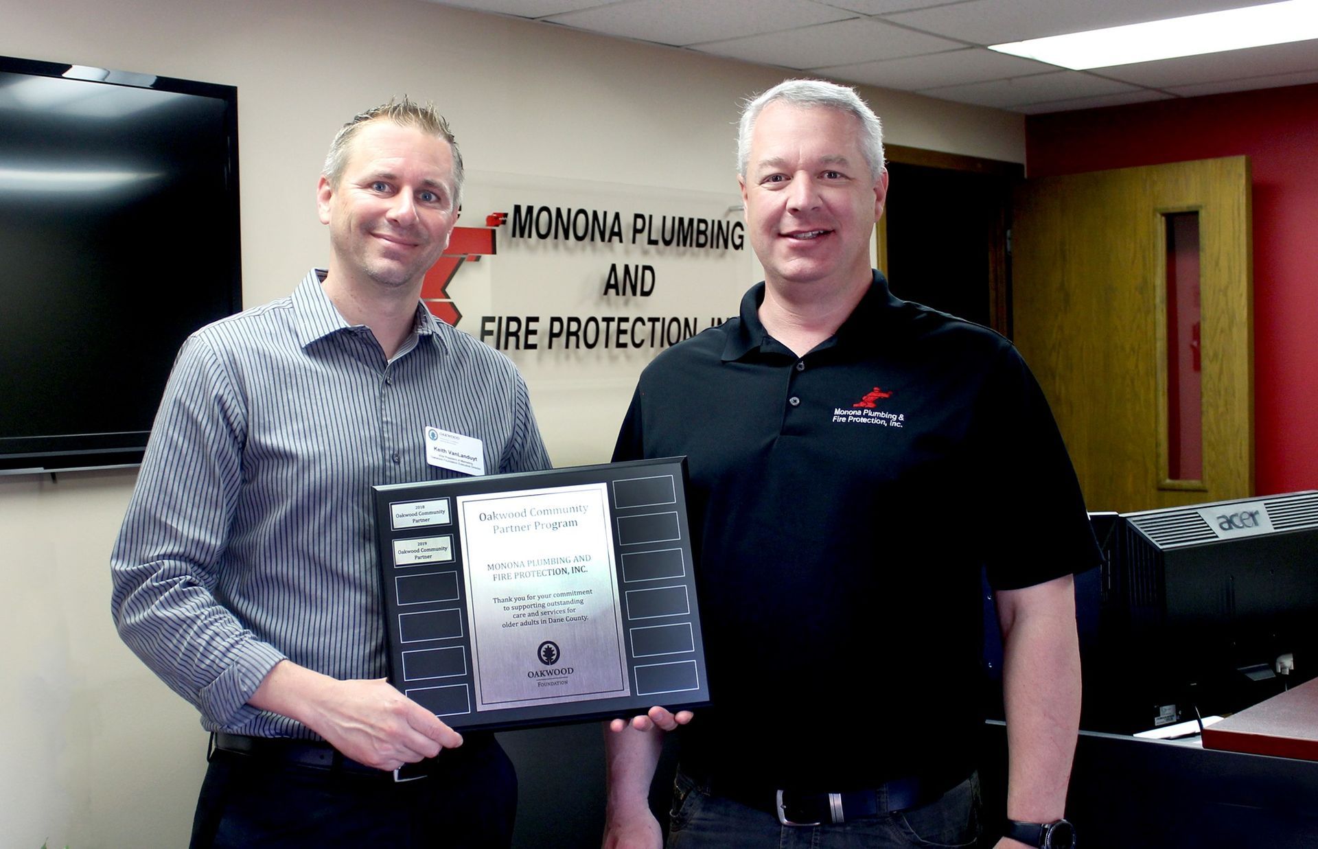 Two men are standing next to each other in front of a sign that says fire protection