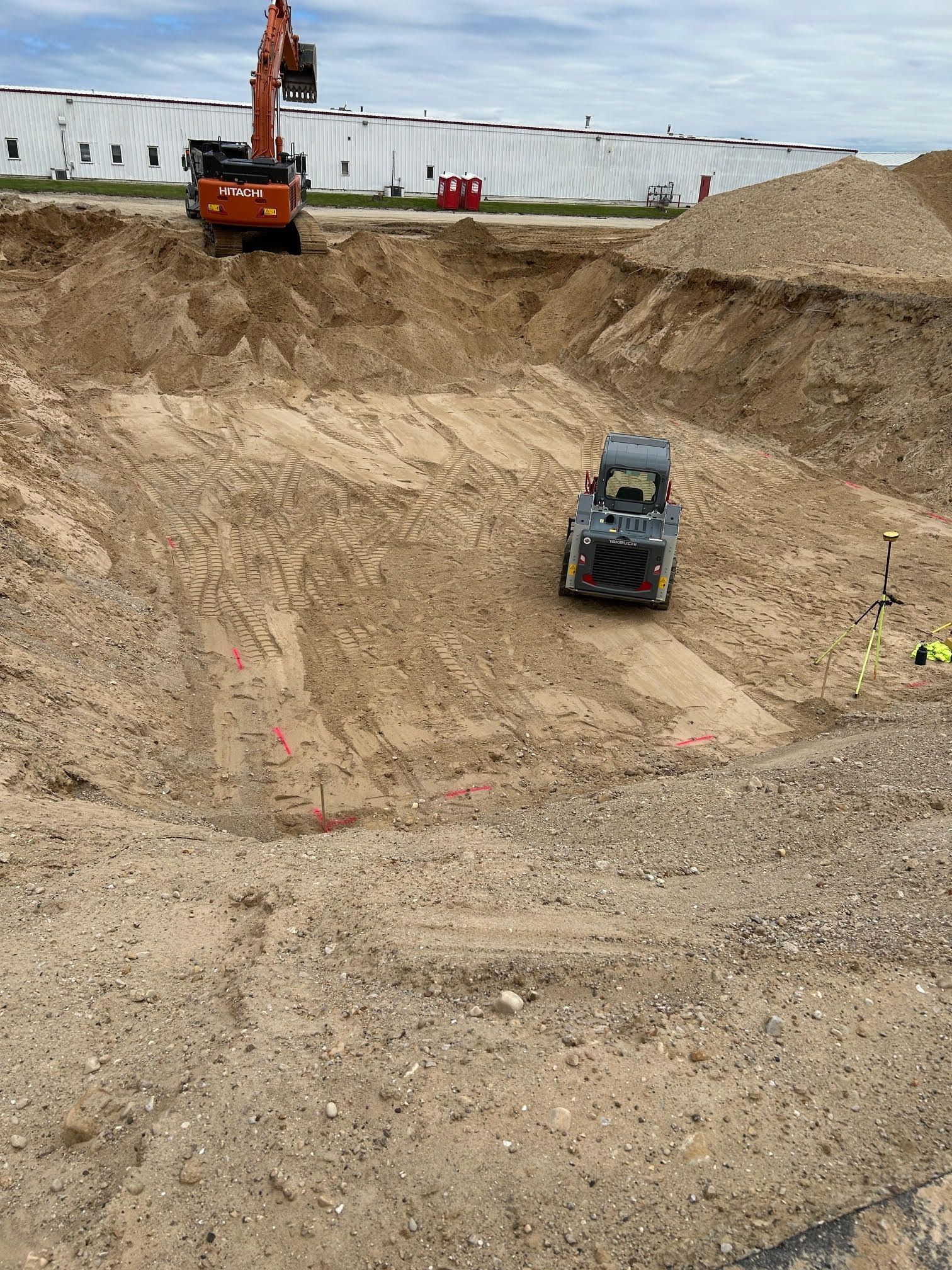 Construction site with excavator and front-end loader in a large dirt pit