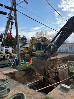 Excavator digging trench beside utility pole