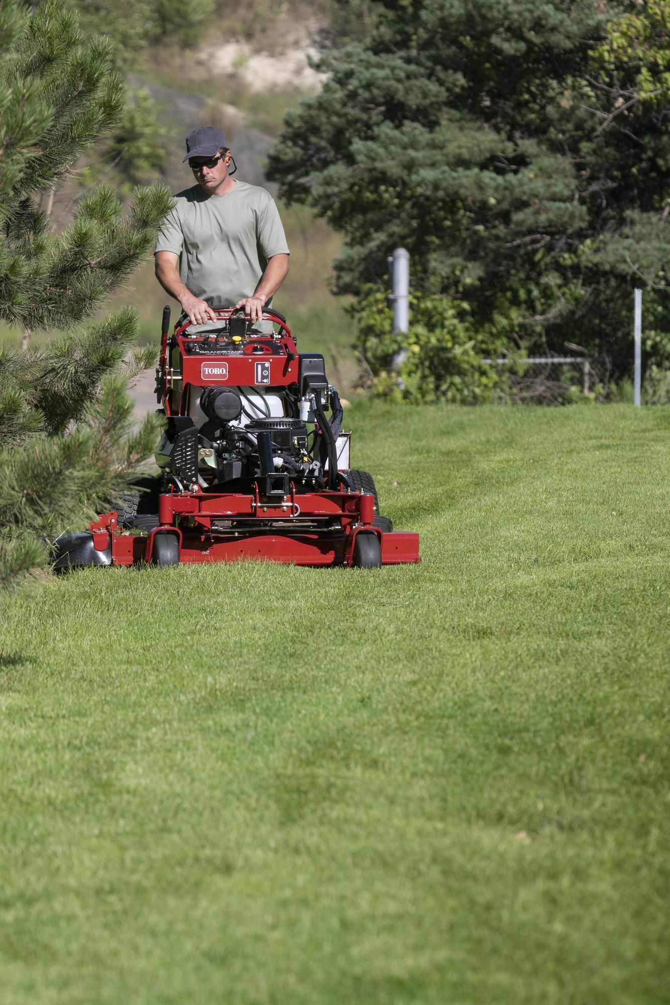 a man is riding a red lawn mower on a lush green field .
