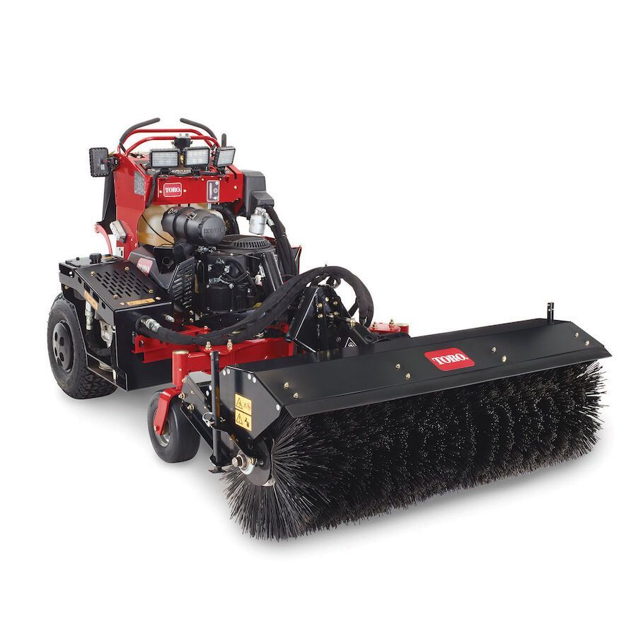 a toro lawn mower with a broom attached to it .