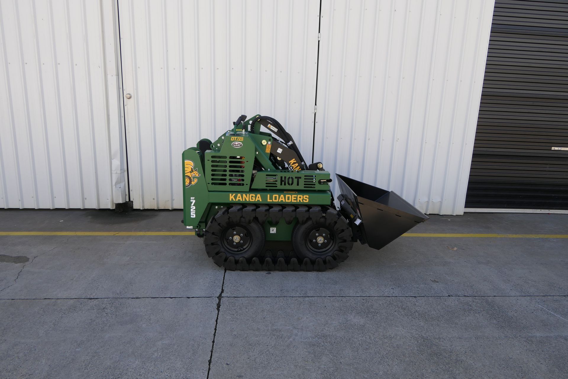 A green tractor is parked in front of a white building