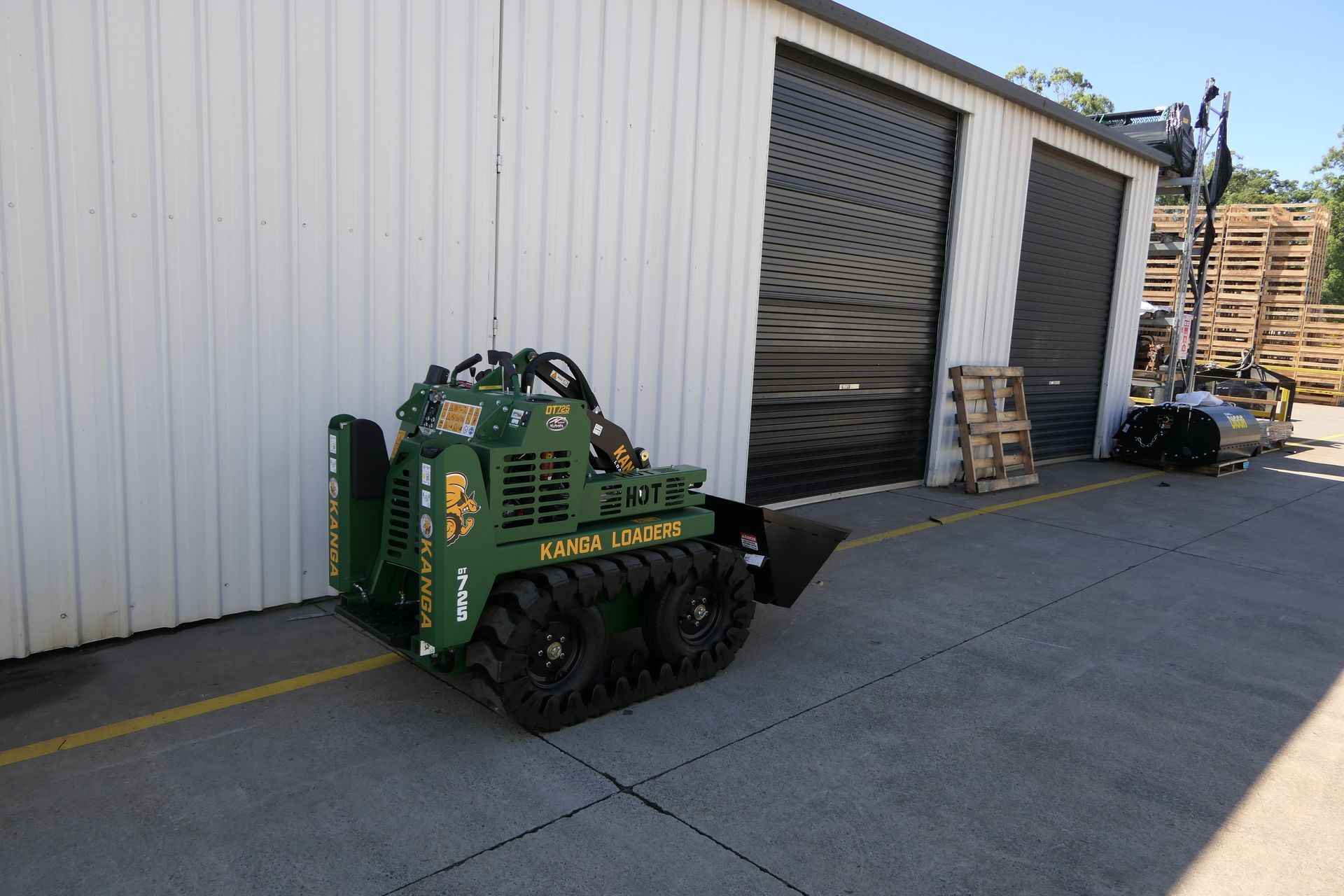 A green tractor is parked in front of a building.