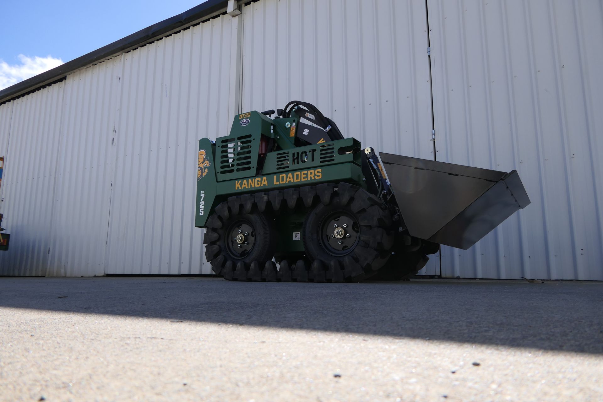 A small green dump truck is parked in front of a building.