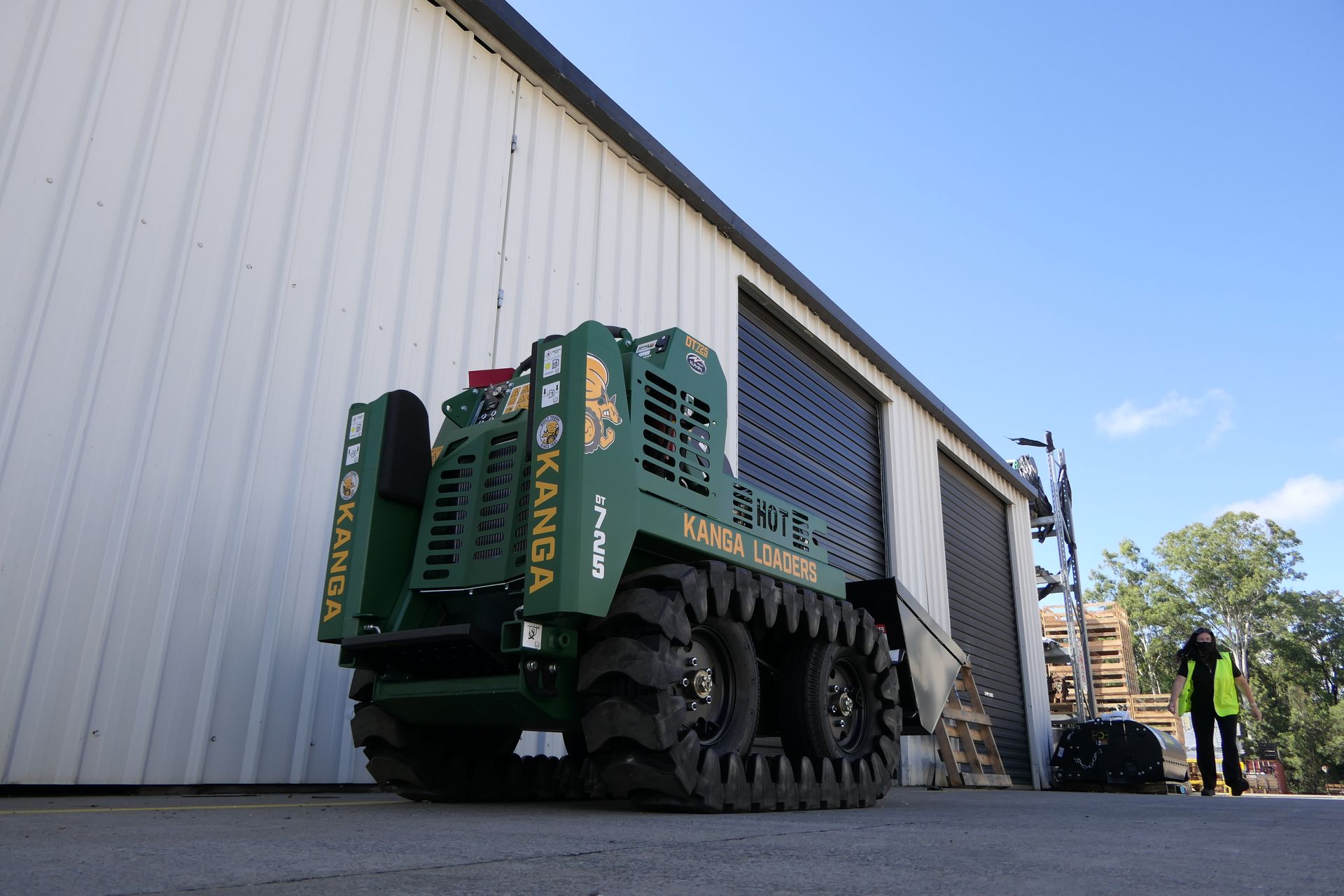 A green tractor is parked in front of a white building