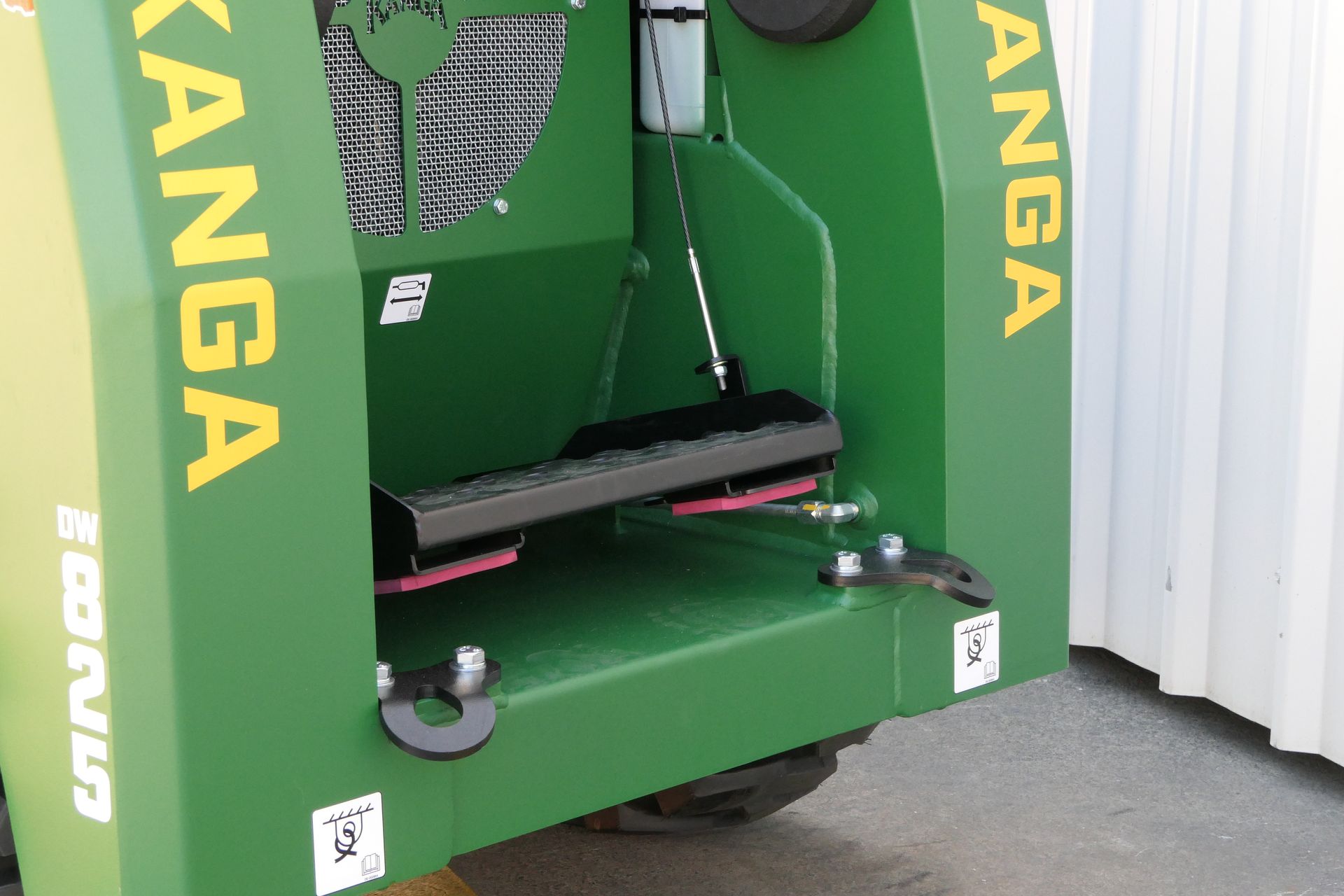 A green Kanga is parked in front of a white wall