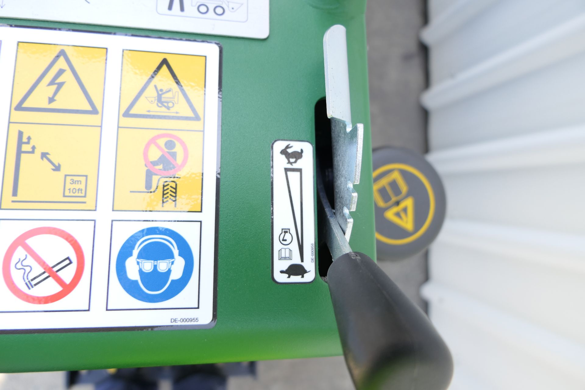 A close up of a green machine with warning signs on it