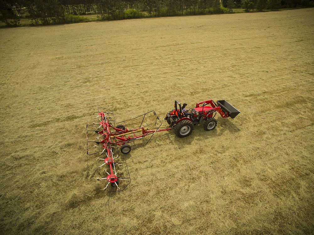 An aerial view of a Massey Ferguson 2600H Series tractor pulling a rake in a field.