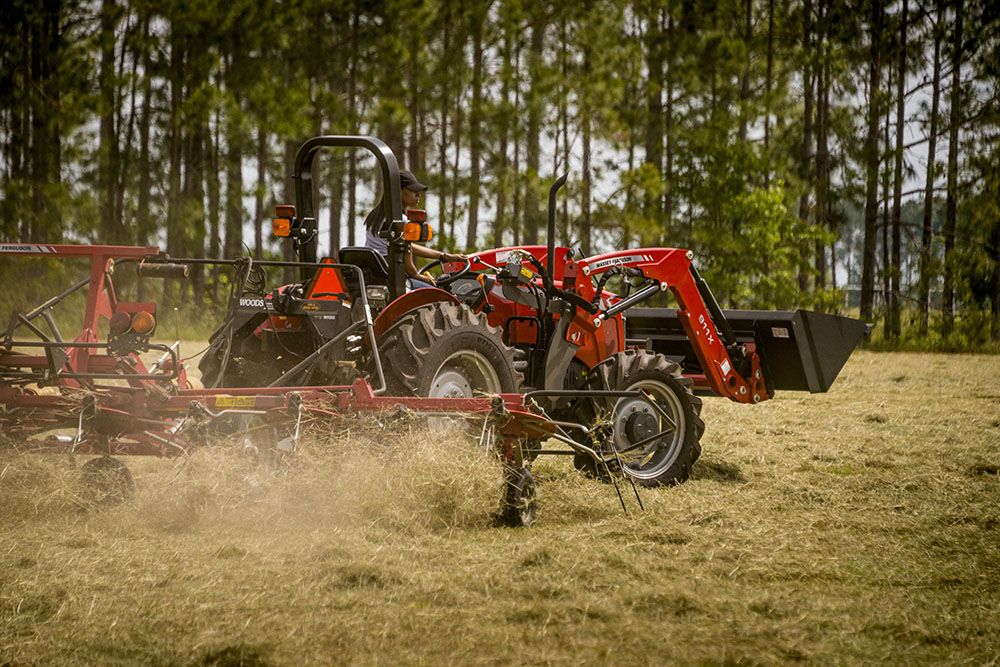 A Massey Ferguson 2600H Series tractor is plowing a field with a rake attached to it.
