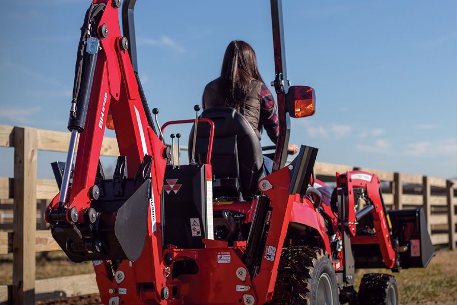 A woman riding a tractor with a backhoe in farm