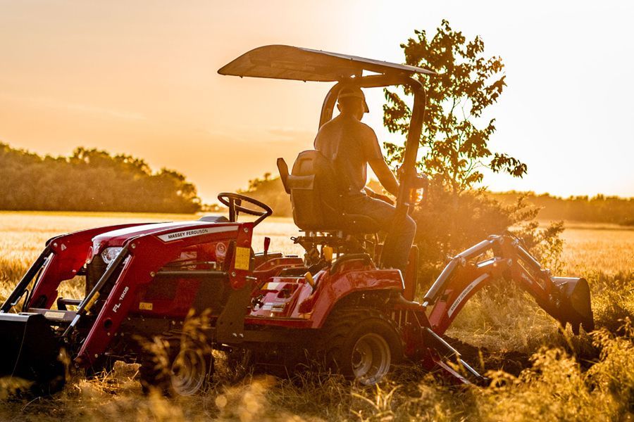 Man riding a tractor with backhoe