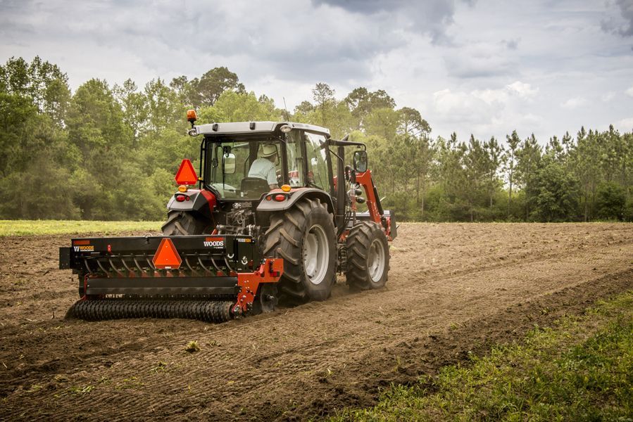 A tractor is plowing a field with a plow attached to it