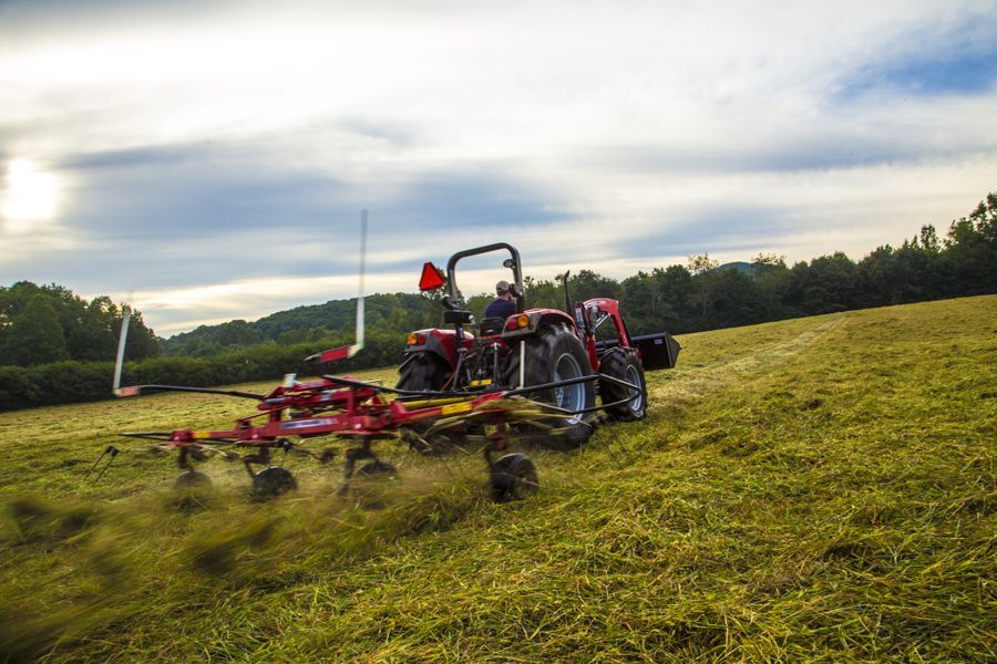 A tractor is raking hay in a field