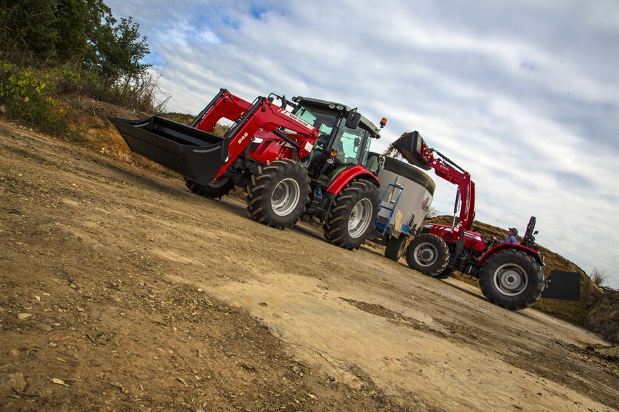 Two tractors are parked next to each other on a dirt road
