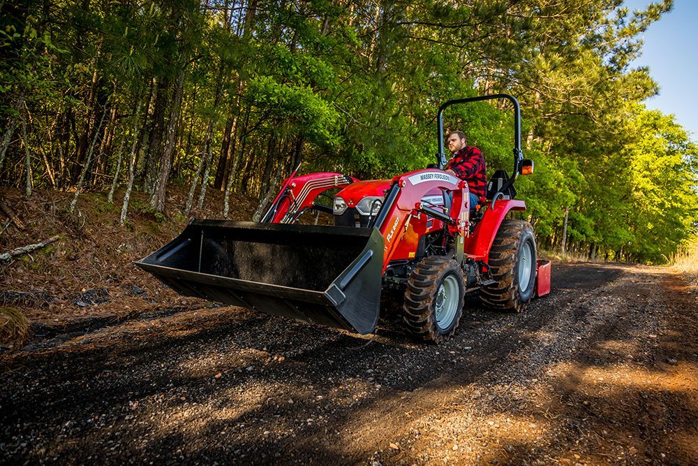 A man is driving a tractor down a dirt road
