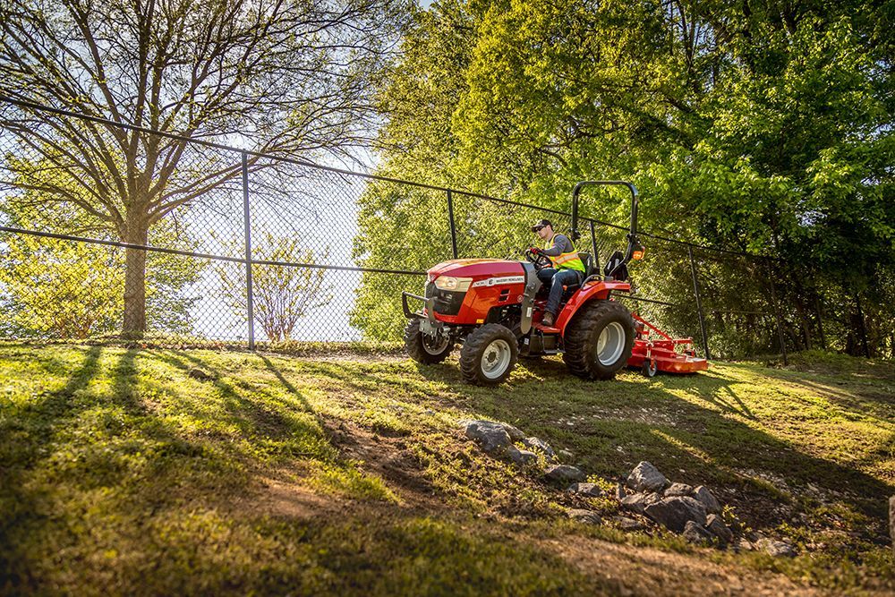 A man is riding a red tractor on a grassy hill