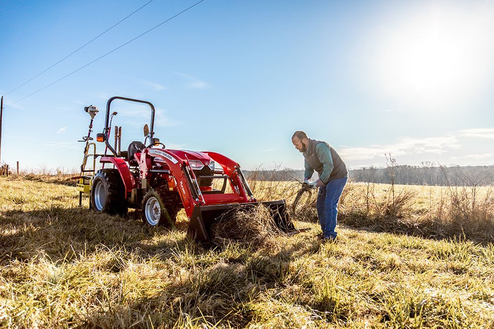 A man is standing next to a tractor in a field