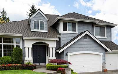 A large gray house with a white garage door and a gray roof.