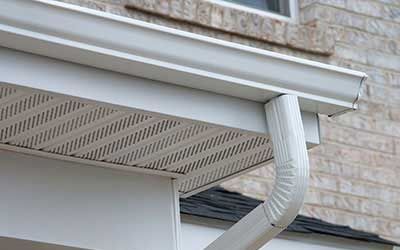 A close up of a white gutter on a brick house.