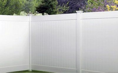 A white vinyl fence is sitting on top of a lush green lawn.