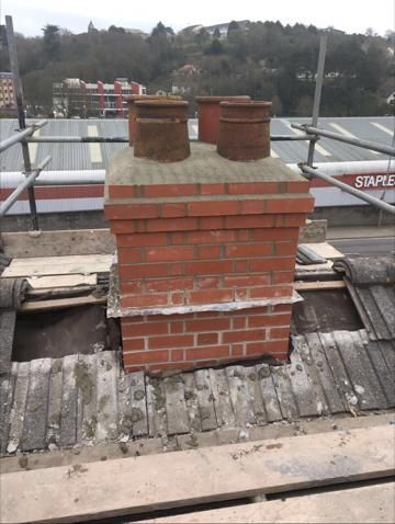 A brick chimney is sitting on top of a wooden roof.