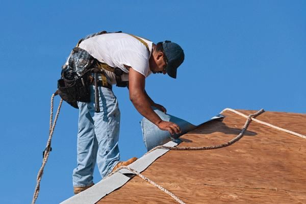 A man is working on a roof with a blue sky in the background