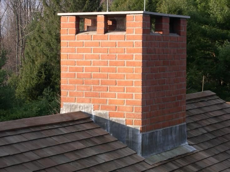 A brick chimney is sitting on top of a wooden roof.