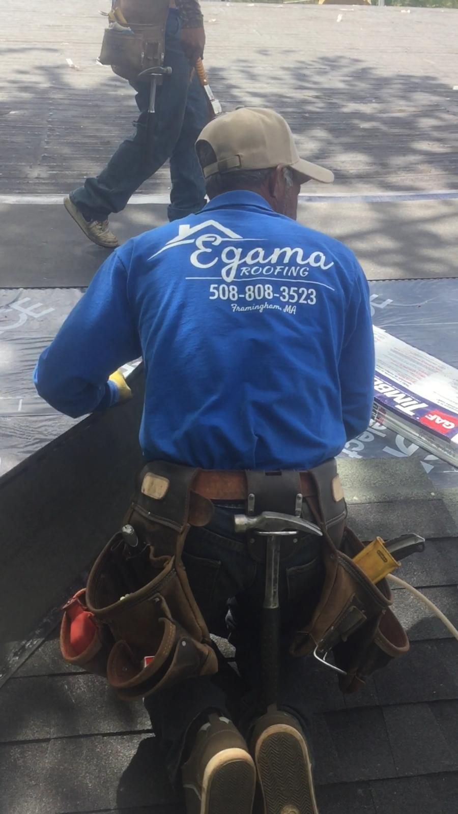 A man in a blue shirt is working on a roof.