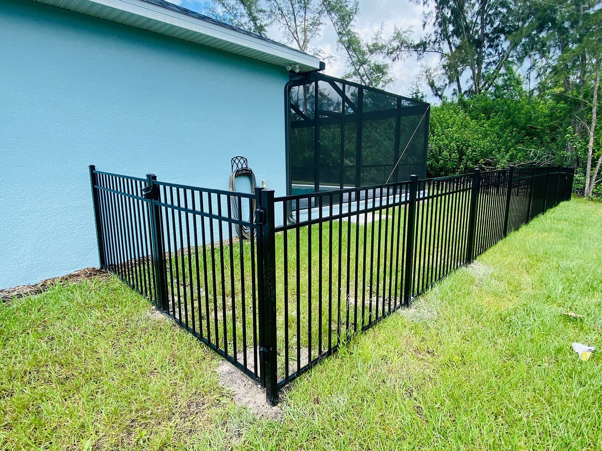 Black metal fence enclosing a small backyard area with a pool screen.